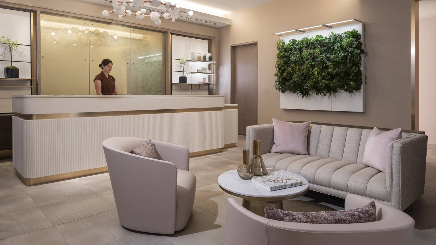 Spa lounge with beige couch and chair and pink pillows.