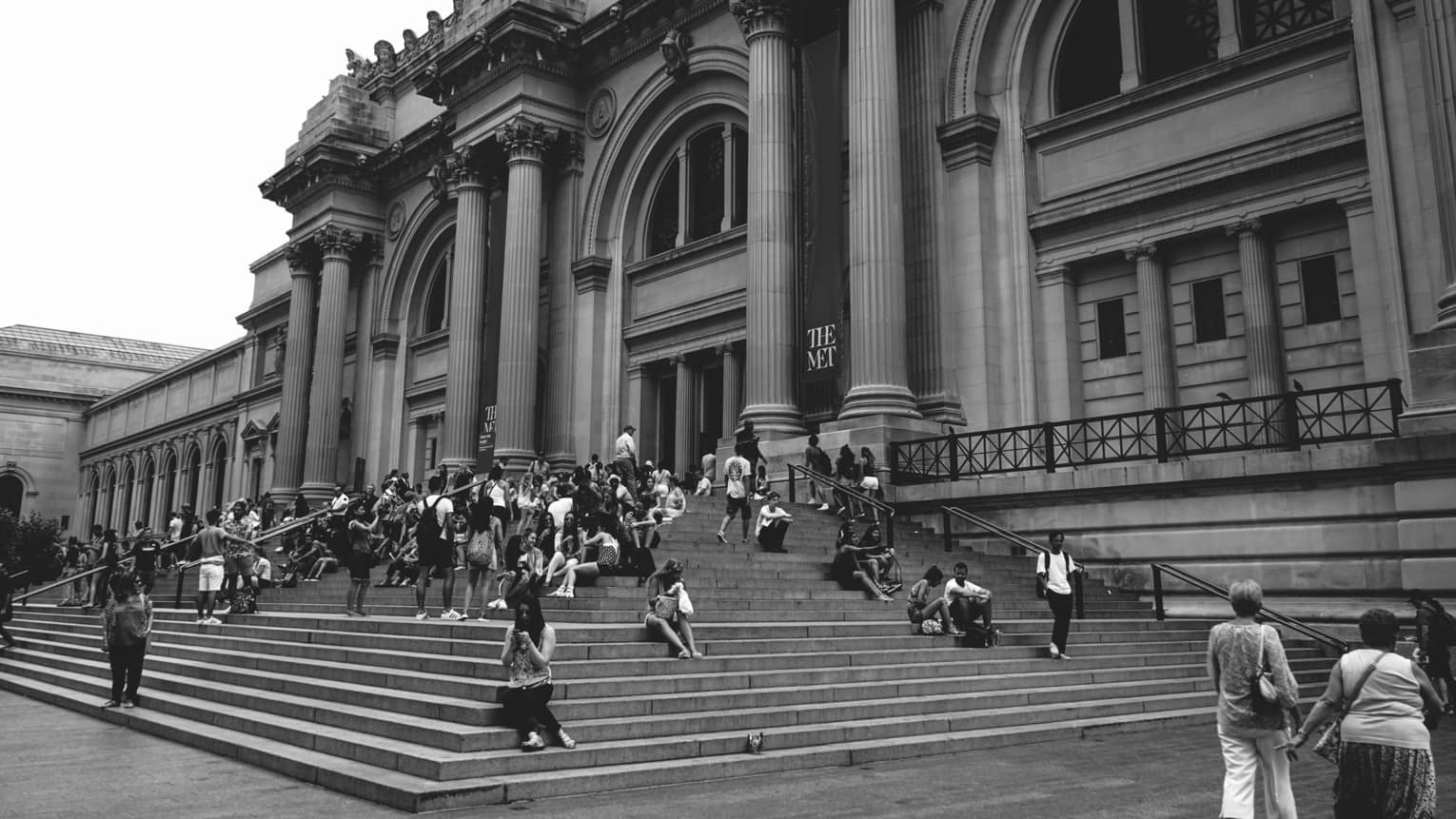 People walking up the steps to a large building with columns.