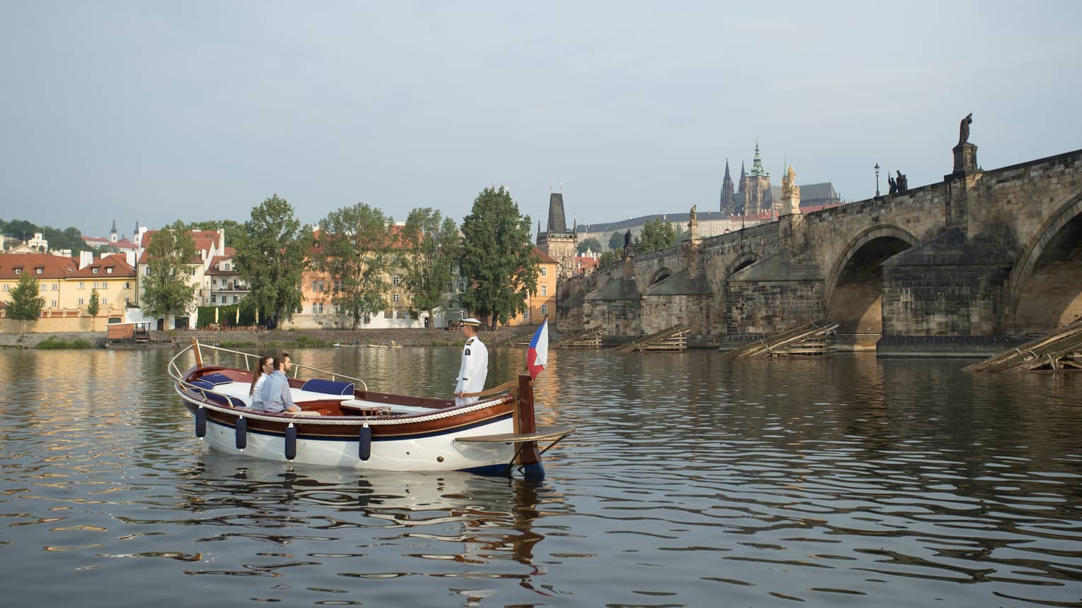 Couple enjoy river boat trip in Prague near small bridge