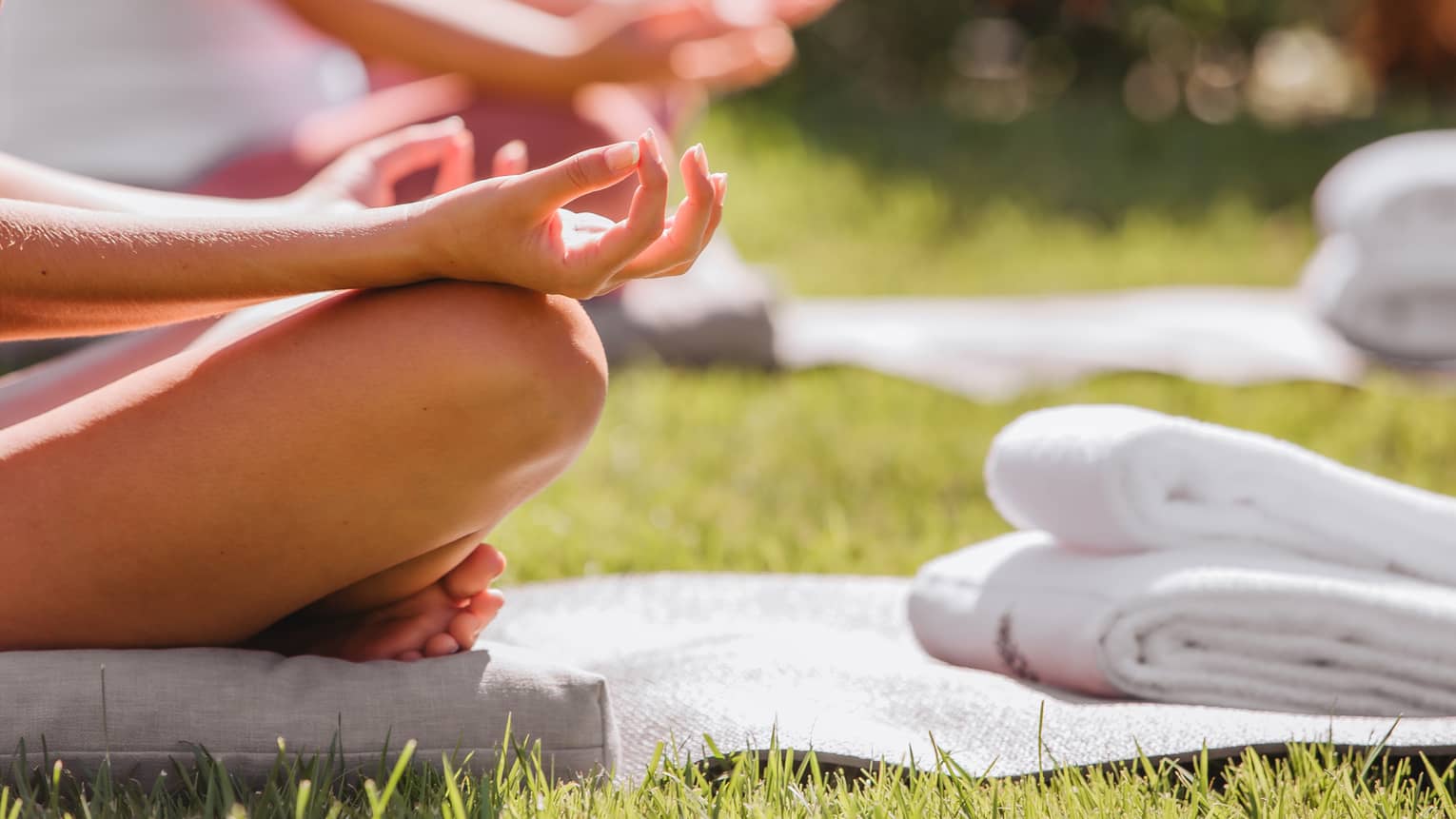 A group doing yoga outside with mats and towels.