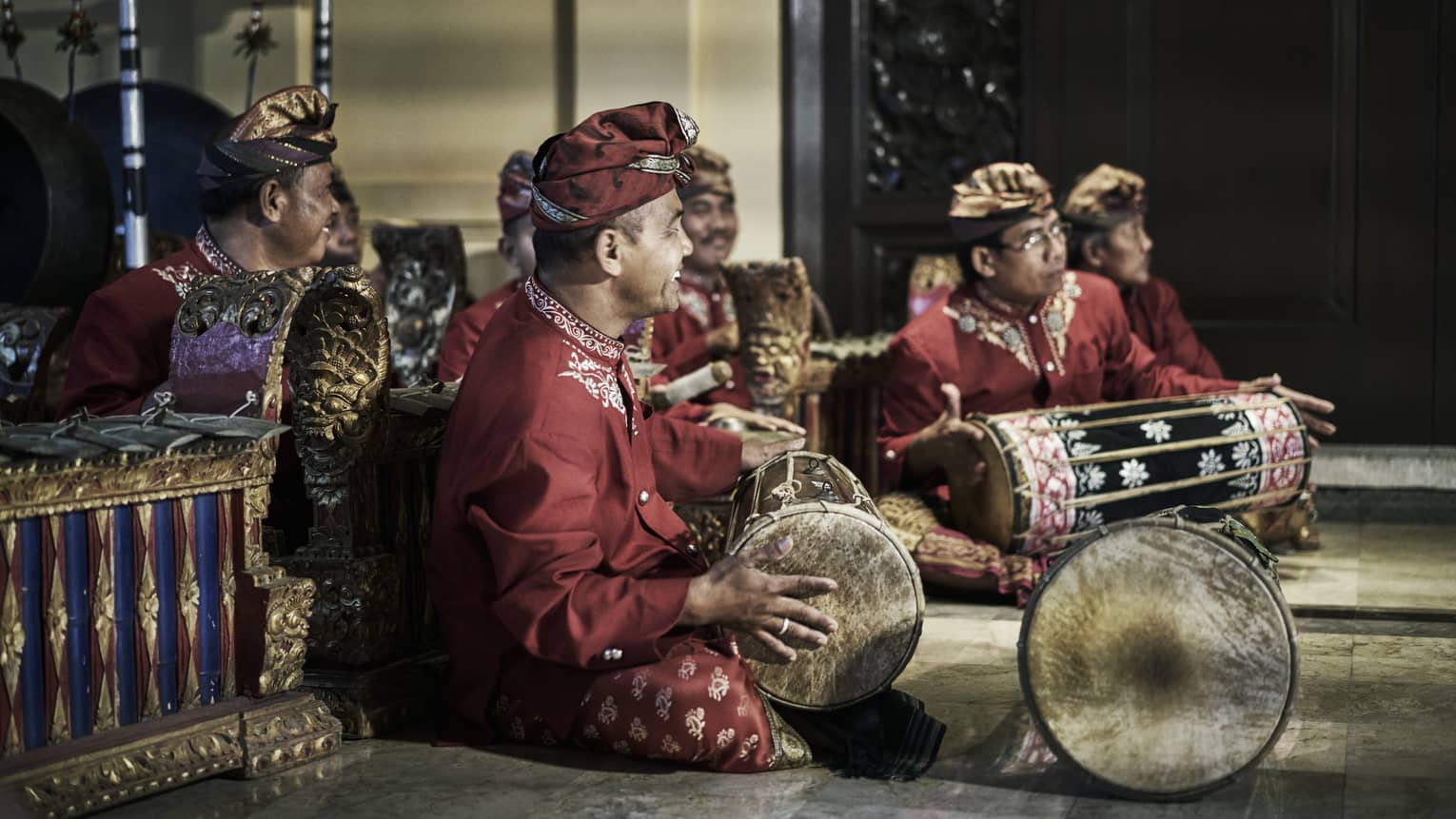 Smiling musical band sits cross legged with hand drums