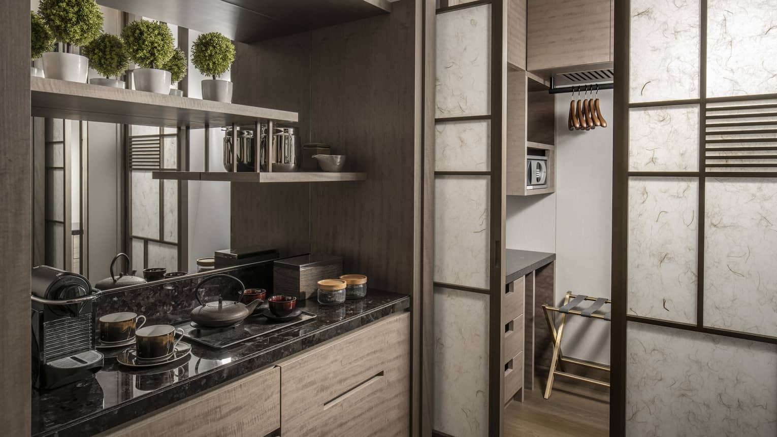 Compact kitchenette with a black granite countertop, open shelving and a pantry area with storage space and a small microwave