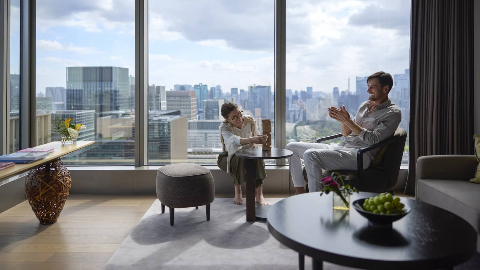 Couple enjoying a relaxing moment in a luxury suite at Four Seasons Hotel Tokyo at Otemachi with city views.