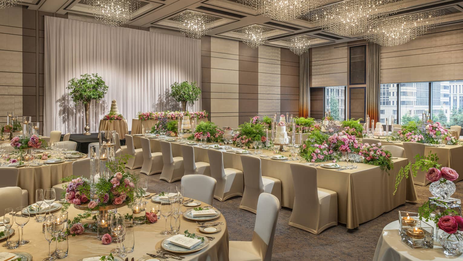 Ballroom set for a wedding with gold tablecloths and pink floral centrepieces