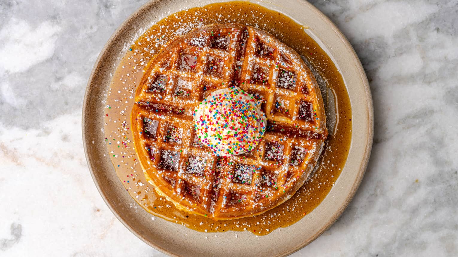 Waffles on a plate with sprinkles and syrup