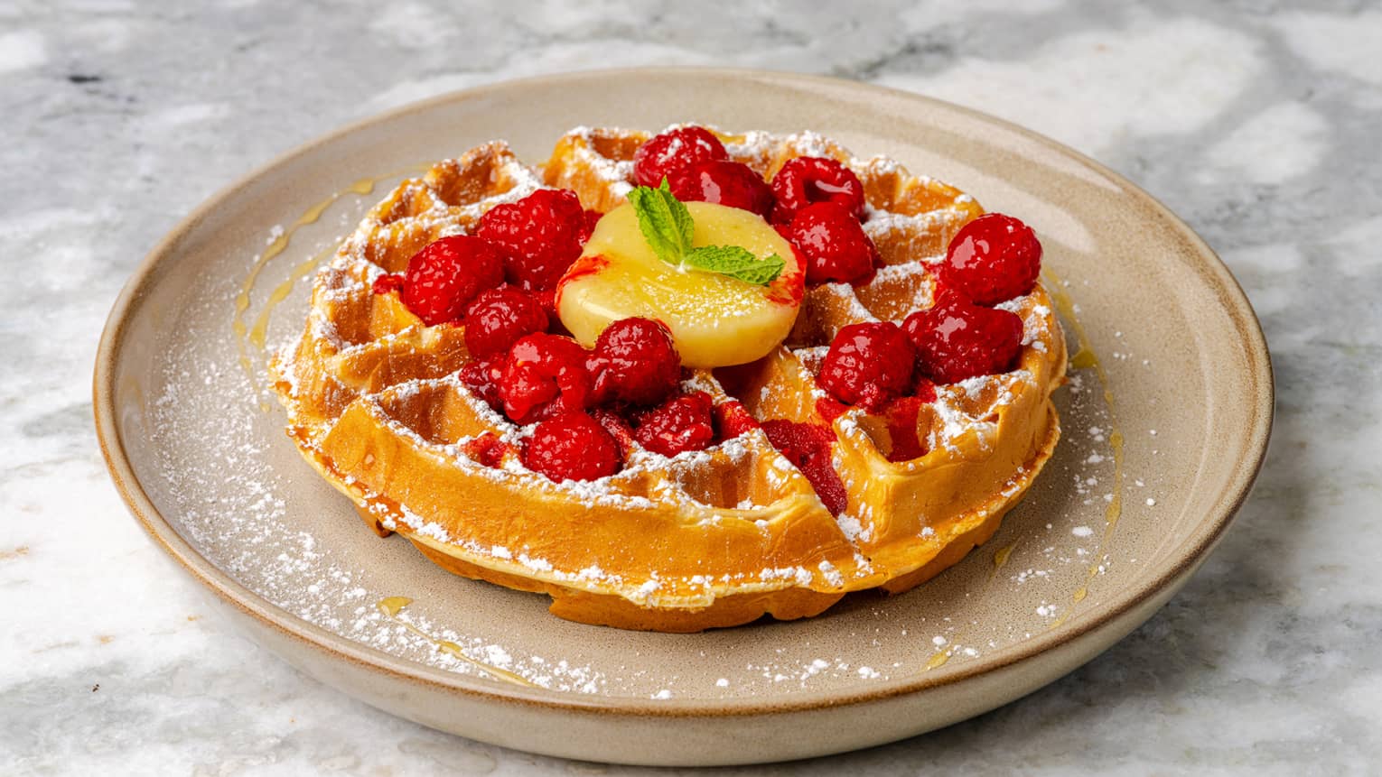 Waffles on a plate with raspberries and powdered sugar