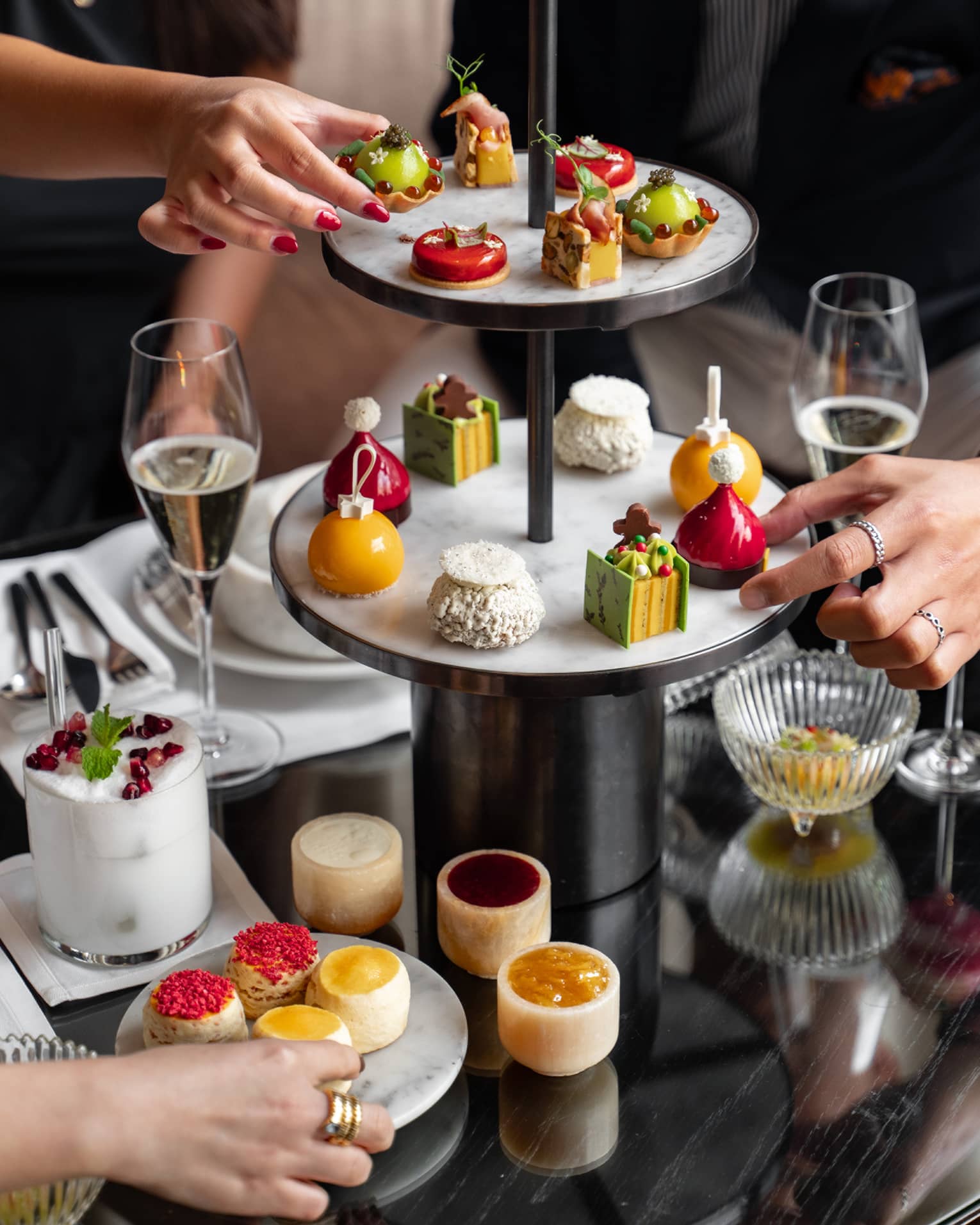A group of people reach for sweets on two-tiered display tower