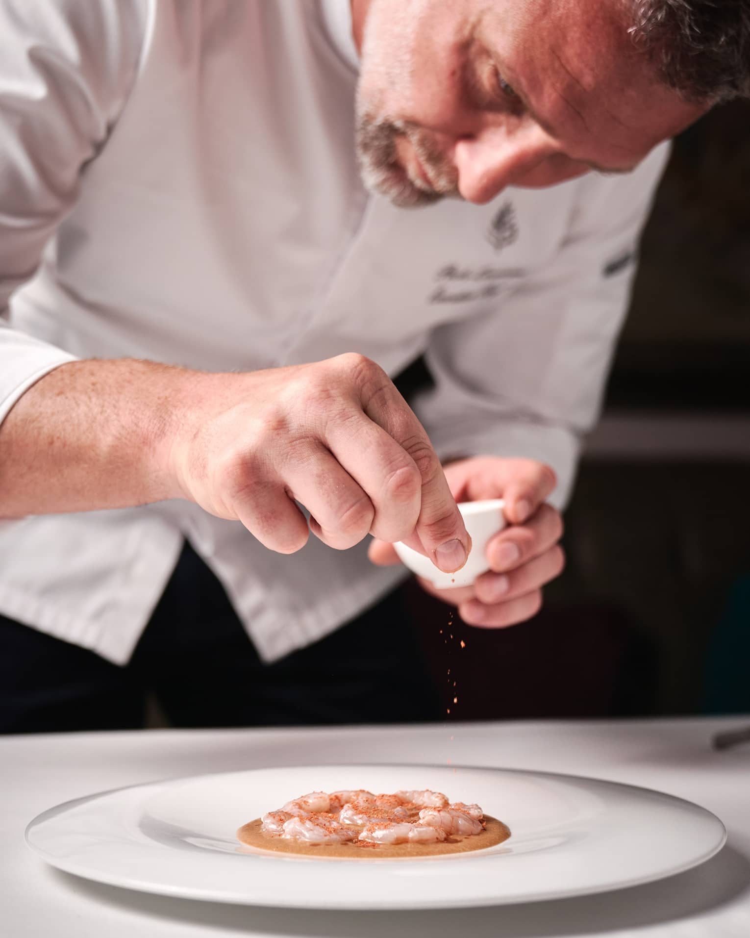 Four Seasons chef garnishing a seafood dish on a white plate