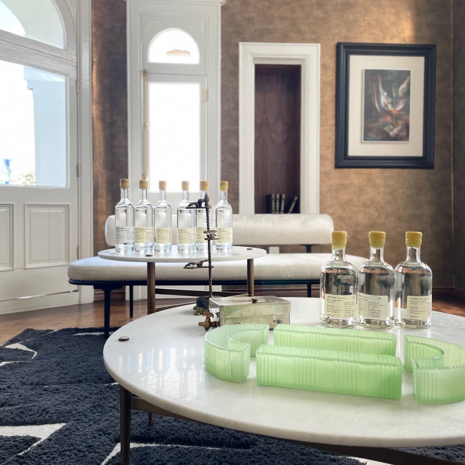 Room with navy rug and brown walls, and a two-tier table with nine bottles on it.