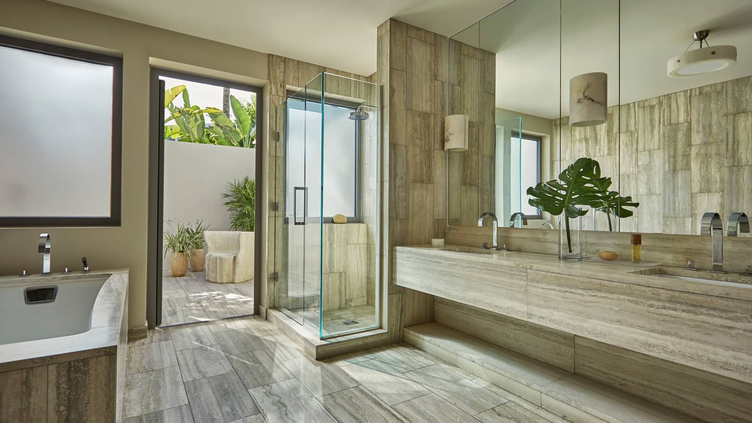 Spacious bathroom with a soaking tub, glass-enclosed shower, double sinks, large mirror and access to a private outdoor terrace