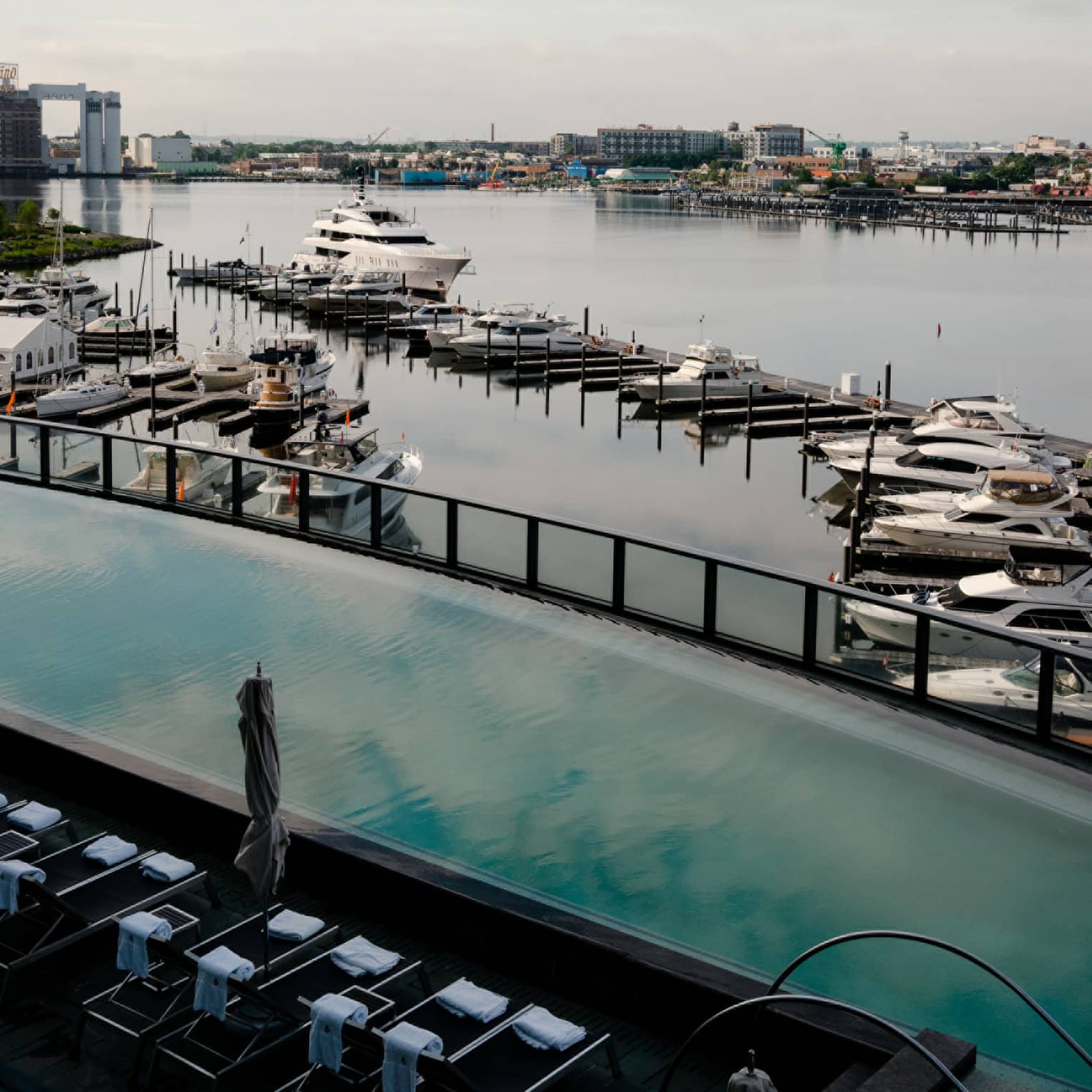 An outdoor pool deck overlooking a harbor view filled with boats