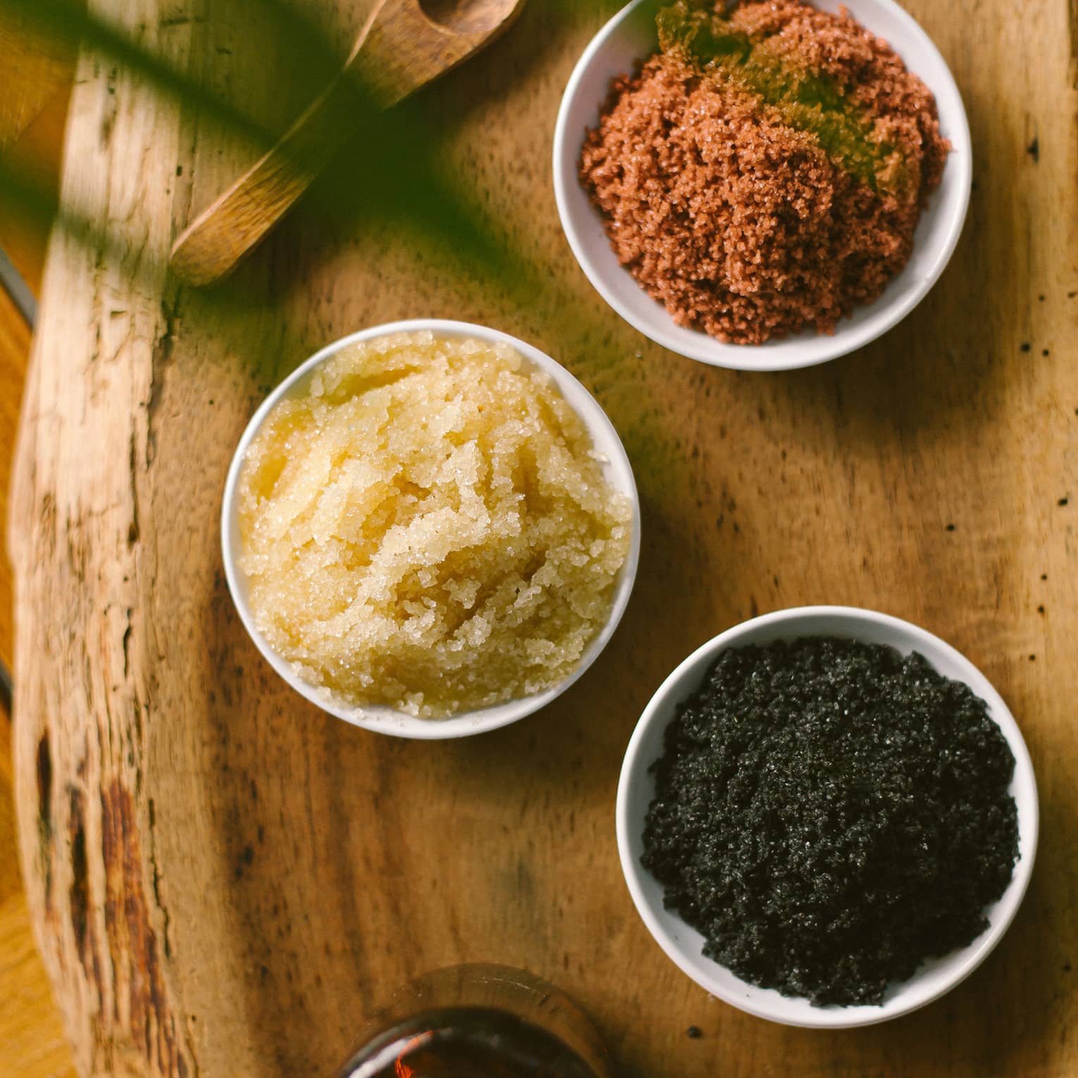 Aerial view of three dishes with salt scrubs on rustic wood platter
