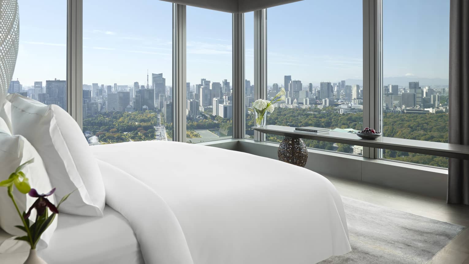 Tokyo suites bedroom with floor-to-ceiling windows offering panoramic city skyline view