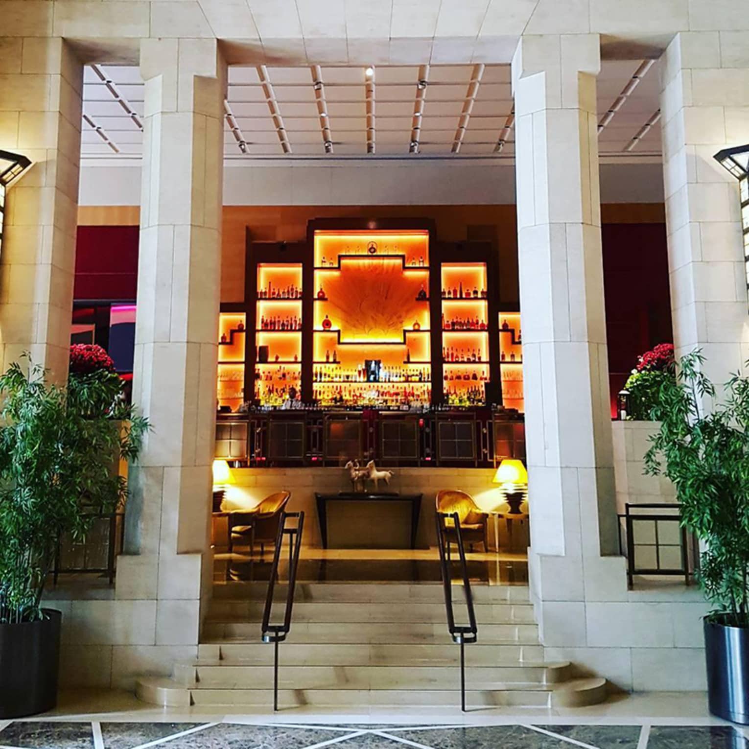 Marble lobby, stone stairs and pillars up to illuminated orange Art Deco style bar