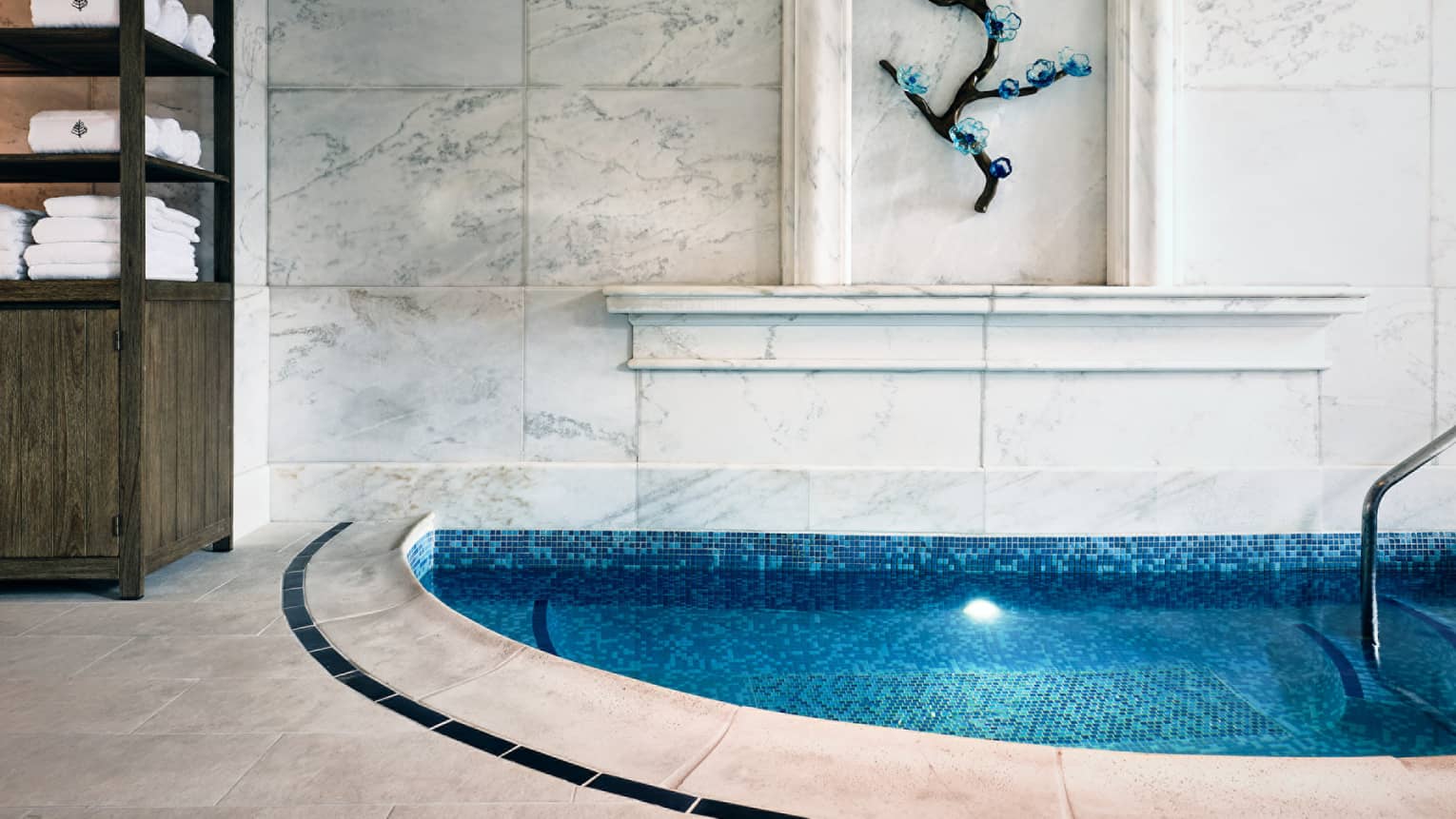 Spa tub with shelves of towels and artwork on the wall.