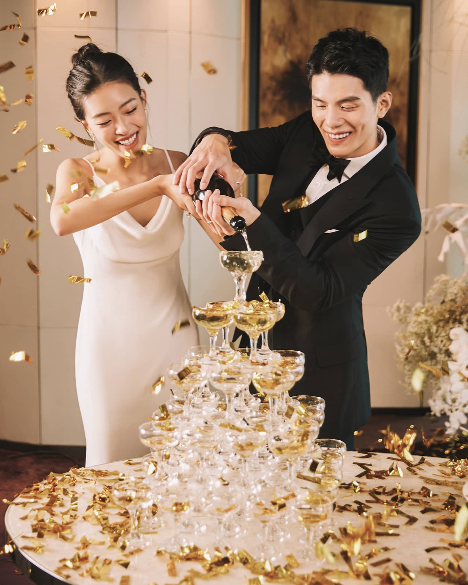 Bride and groom pour champagne into a champagne tower