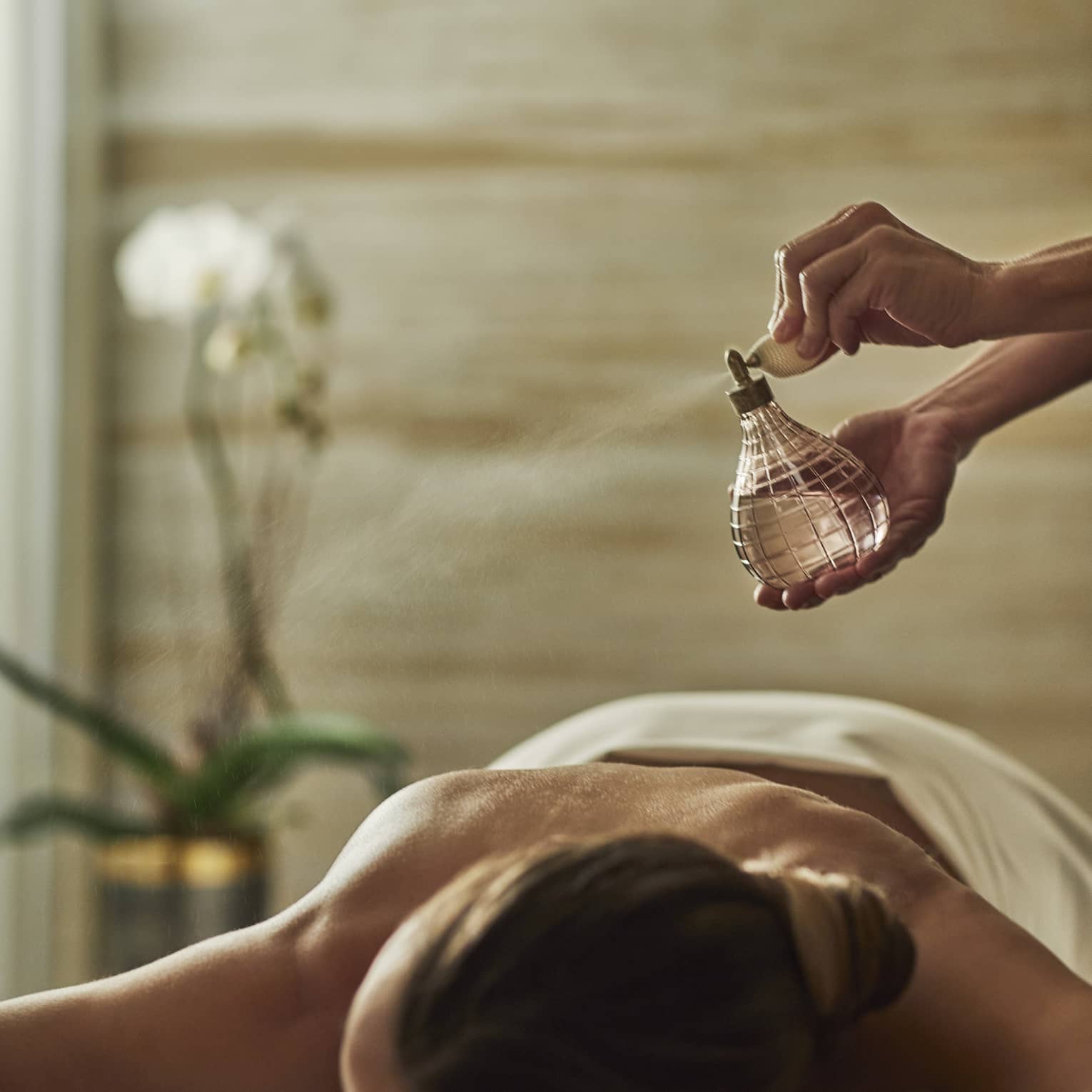 A woman having mist sprayed over her on a spa treatment room.