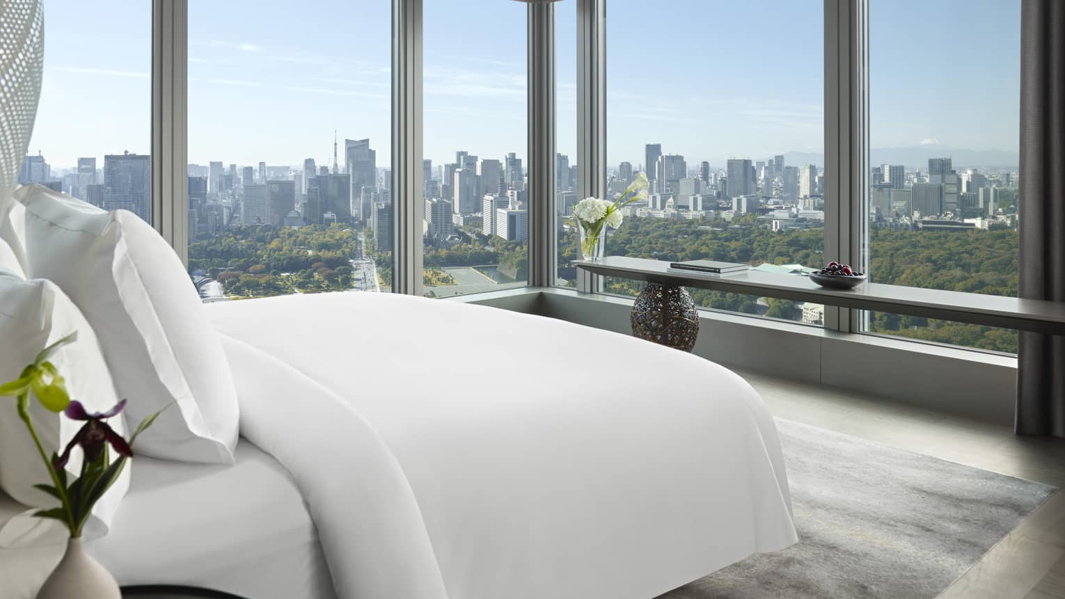 Tokyo suites bedroom with floor-to-ceiling windows offering panoramic city skyline view