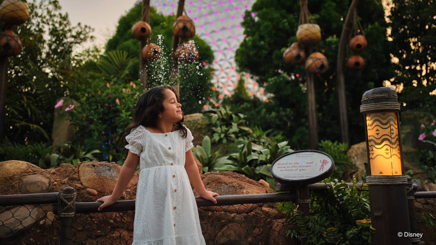 Young child stands in front of a garden with EPCOT's Spaceship Earth in the background