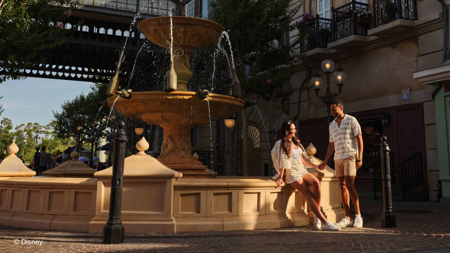 Couple sits on the ledge of a fountain