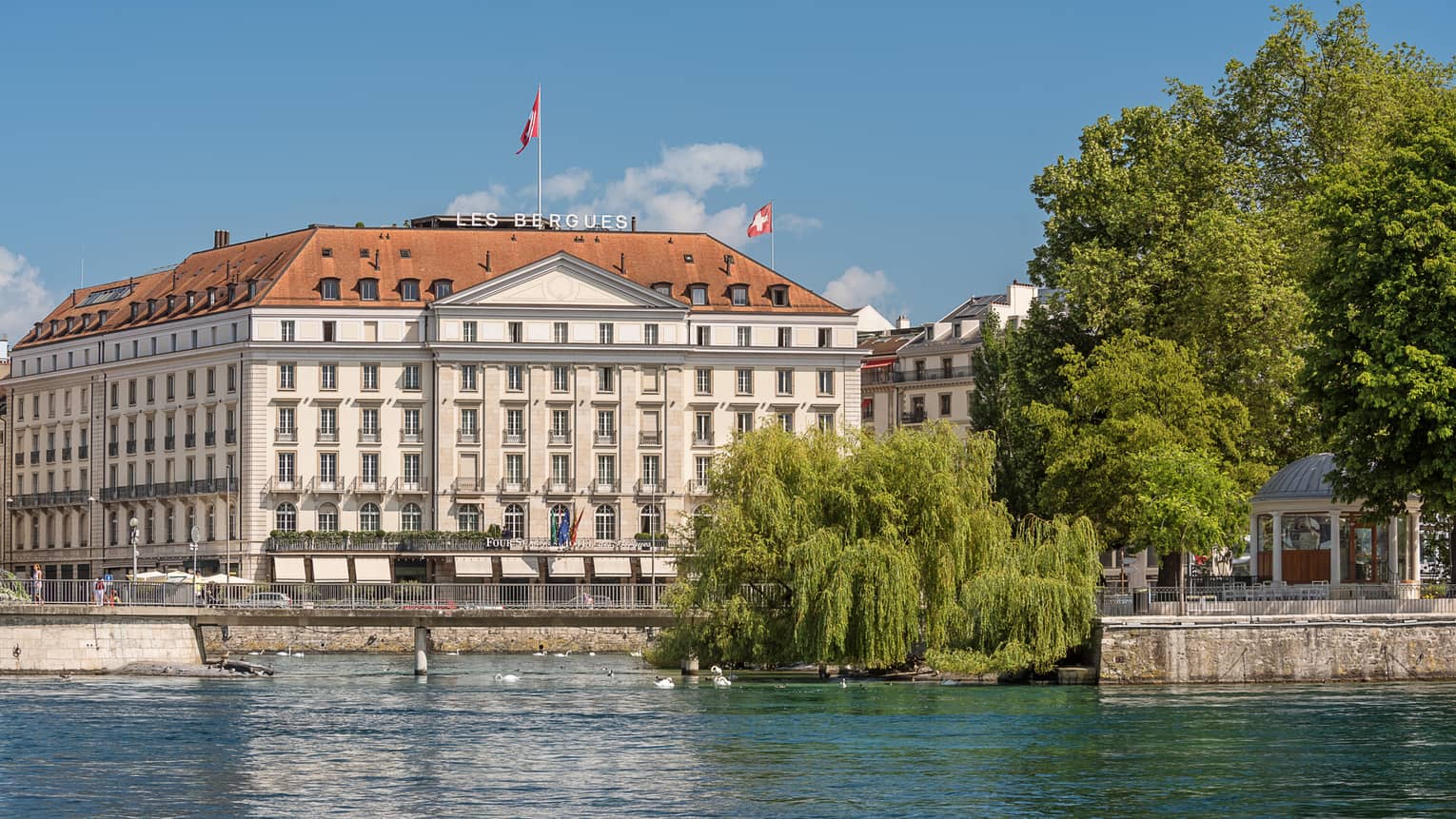 Exterior view of Four Seasons Hotel des Bergues historic building on sunny day by lake