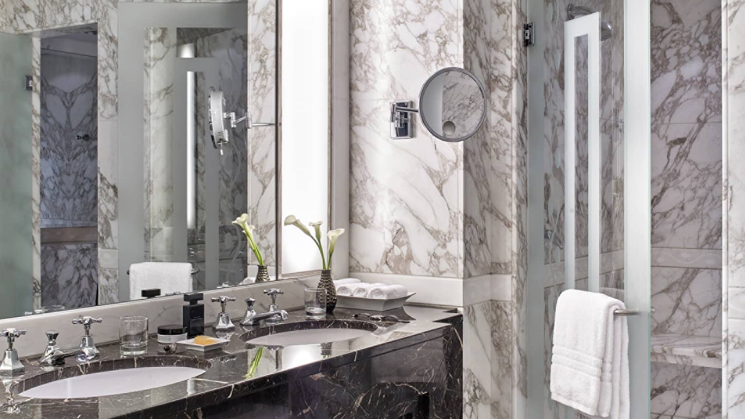 Luxurious marble bathroom with double vanity, glass shower and fresh calla lilies in a vase