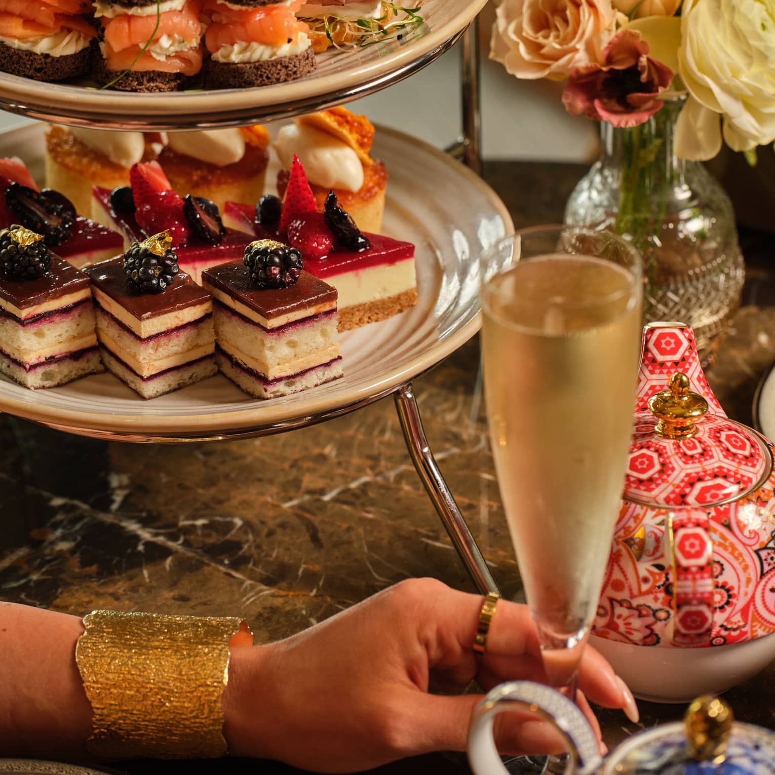 A three-tiered display of sweets beside a vase of flowers
