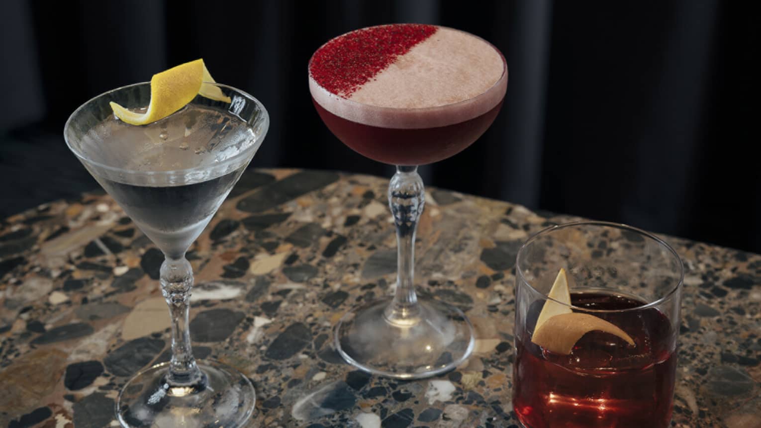 Three different cocktails sit on a marble table