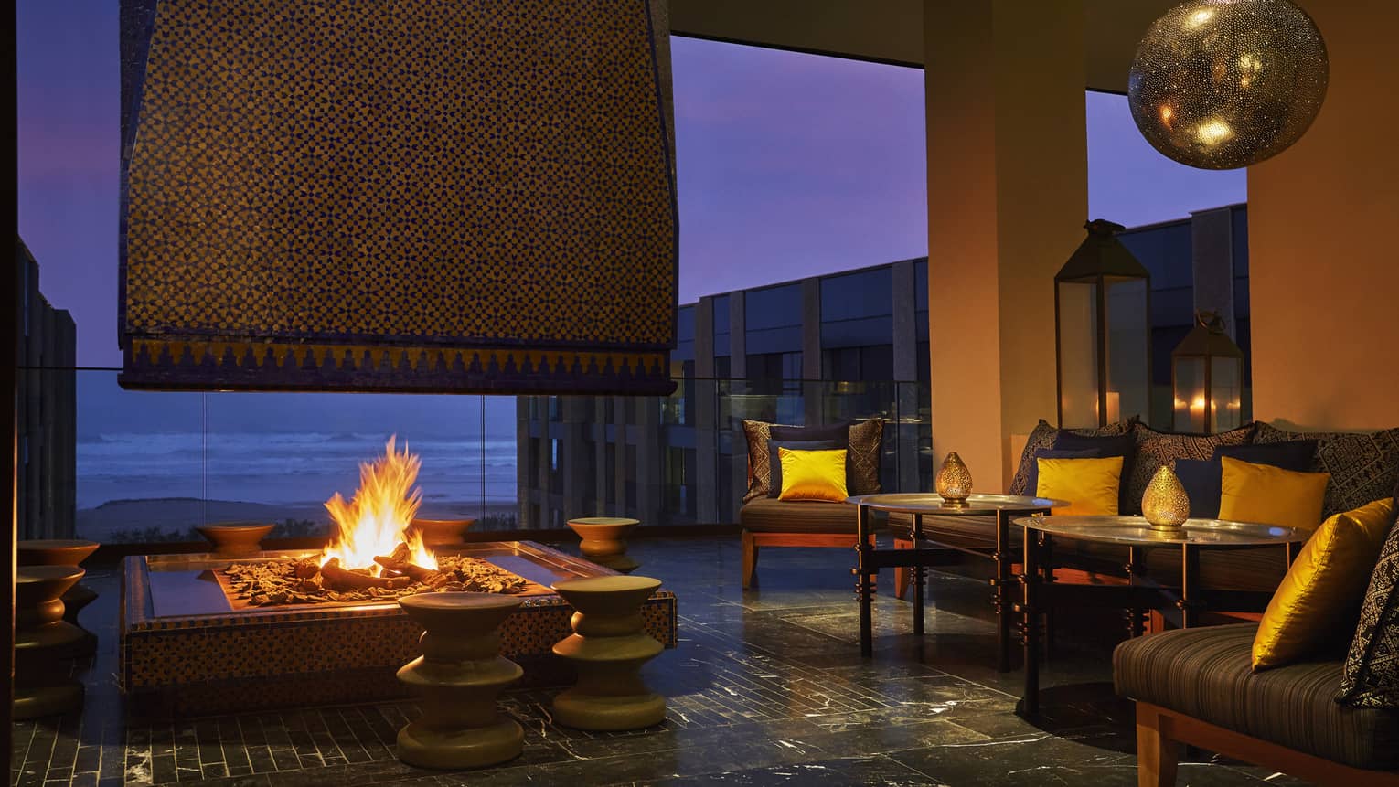 Patios sofas, beaches around large outdoor fireplace on Mint terrace at night