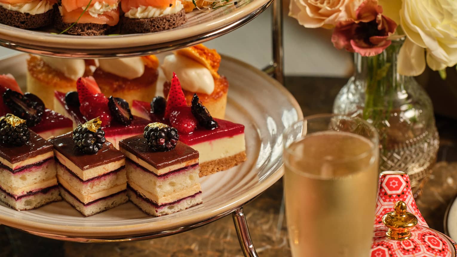 A three-tiered display of sweets beside a vase of flowers