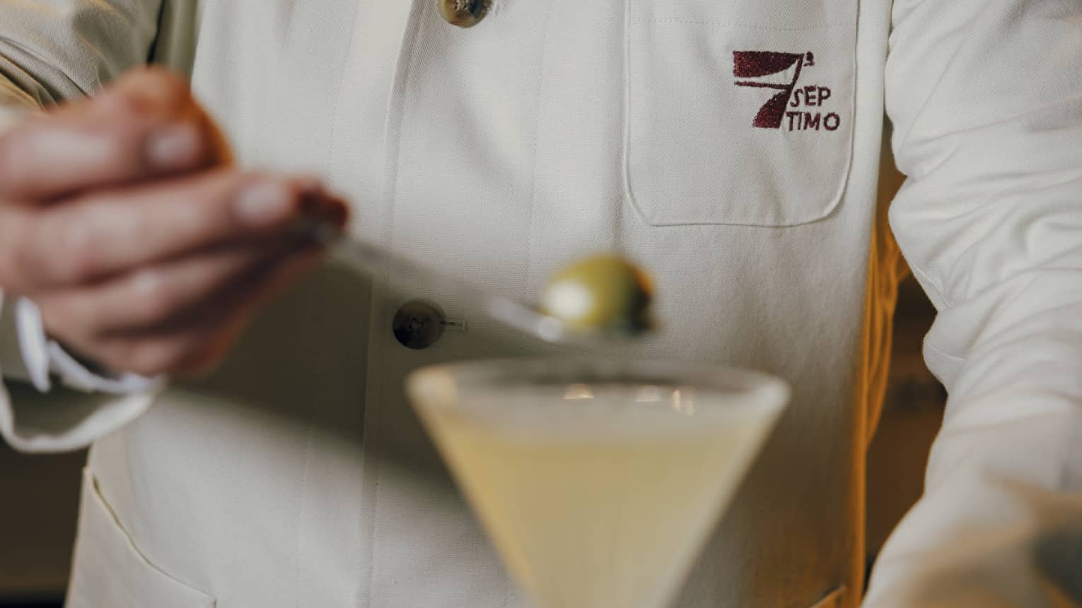 Bartender placed an olive into a Martini