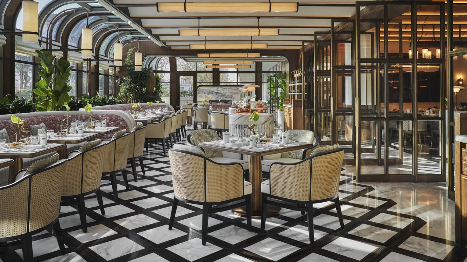 Restaurant dining room with black-and-white tiled floors, wicker-backed dining chairs and a conservatory-style ceiling