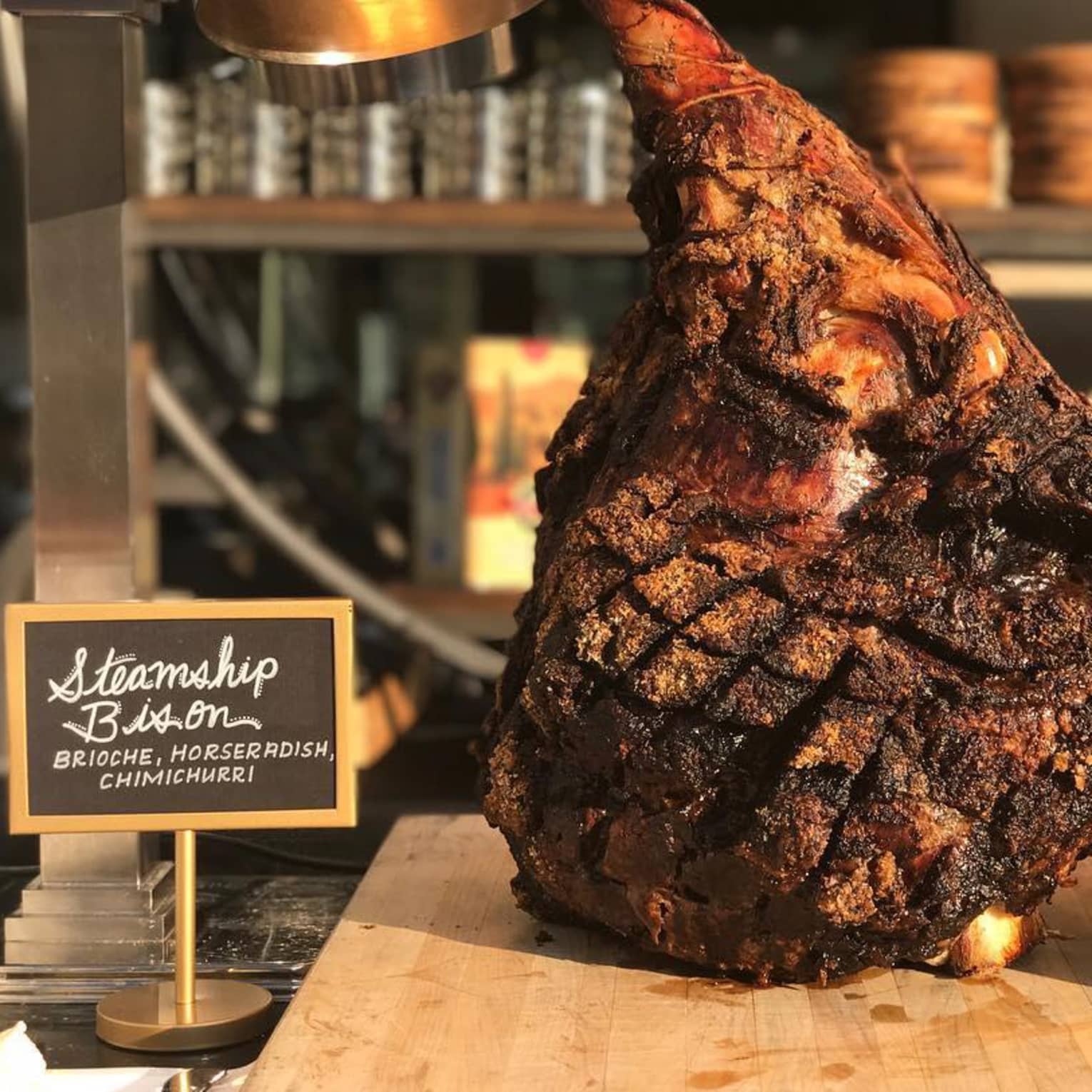 Charred Steamship Bison chop displayed on wood board on counter with sign