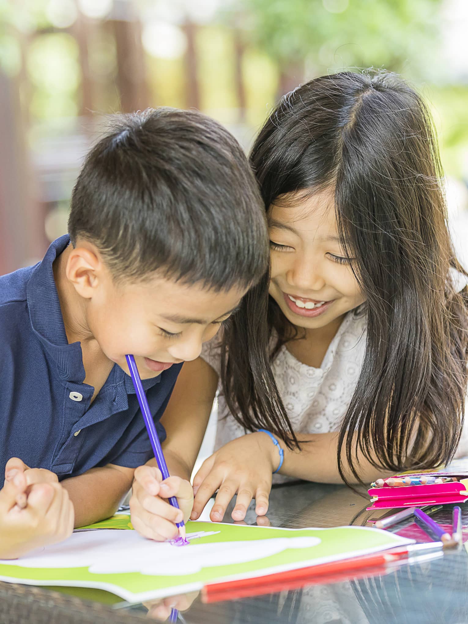 Smiling young boy and girl colouring in book with crayon
