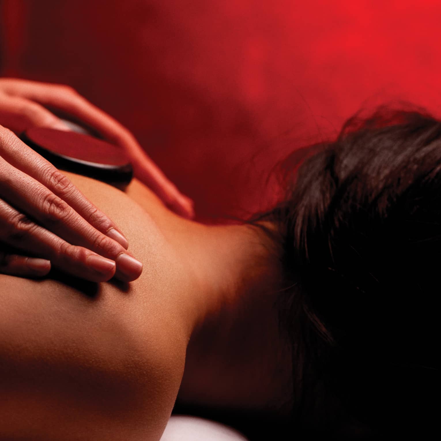 Hands rub woman's bare shoulders during Fusion Massage in spa
