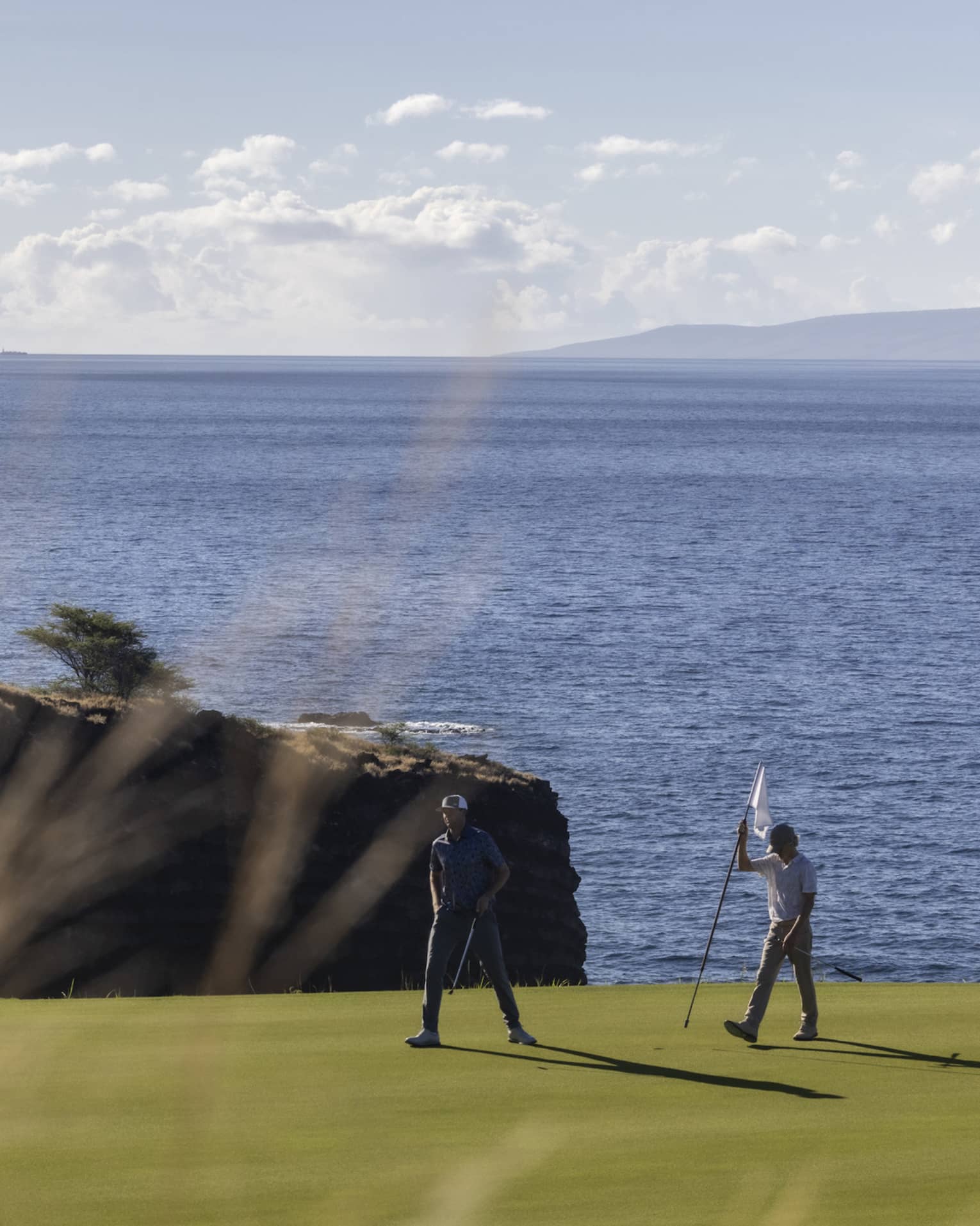 Two golfers on oceanside green at Four Seasons Resort Lanai