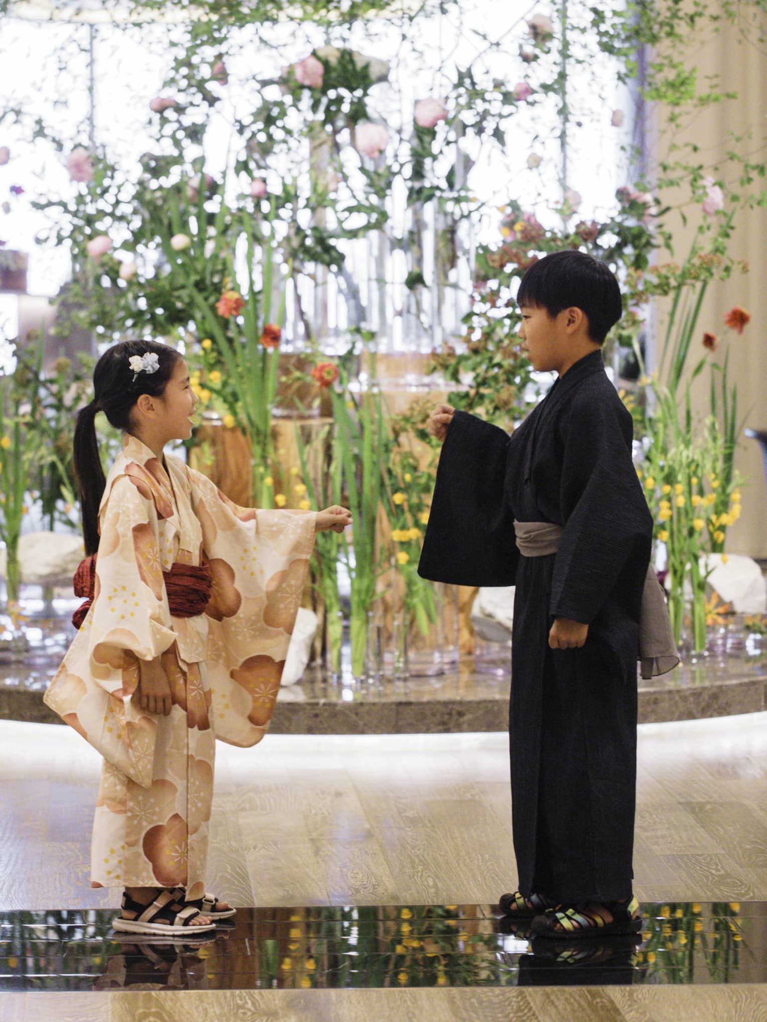 Two children dressed in yukatas stand in hotel lobby in front of elaborate floral floor display