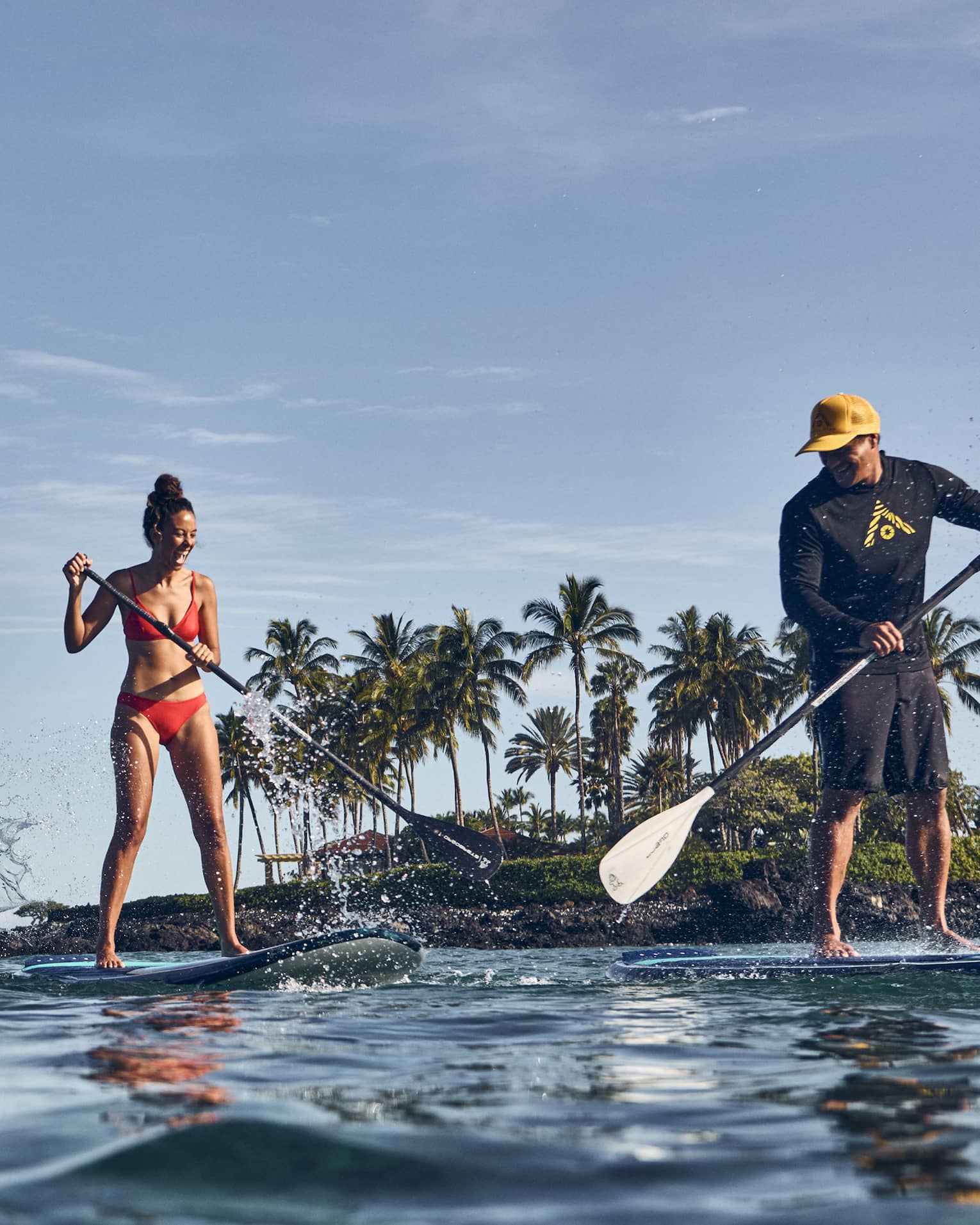 Three people paddle board in tropical location in ocean