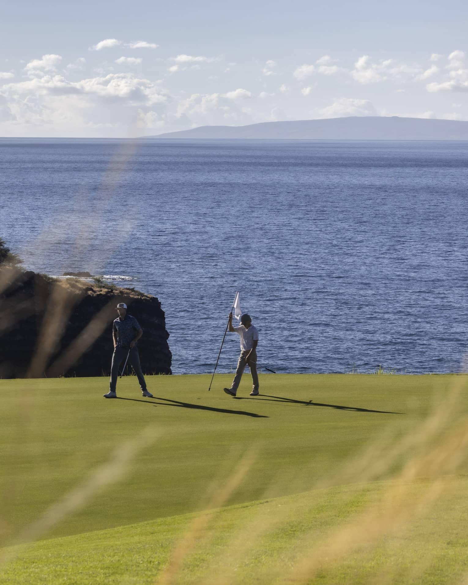 Two golfers on oceanside green at Four Seasons Resort Lanai