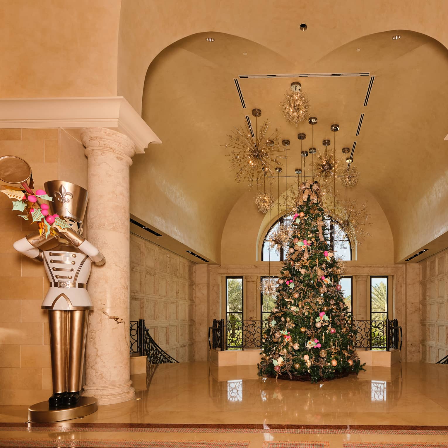 Hotel lobby decorated for the holidays with a large Christmas tree in the centre and two large gold-and-white toy soildier statues