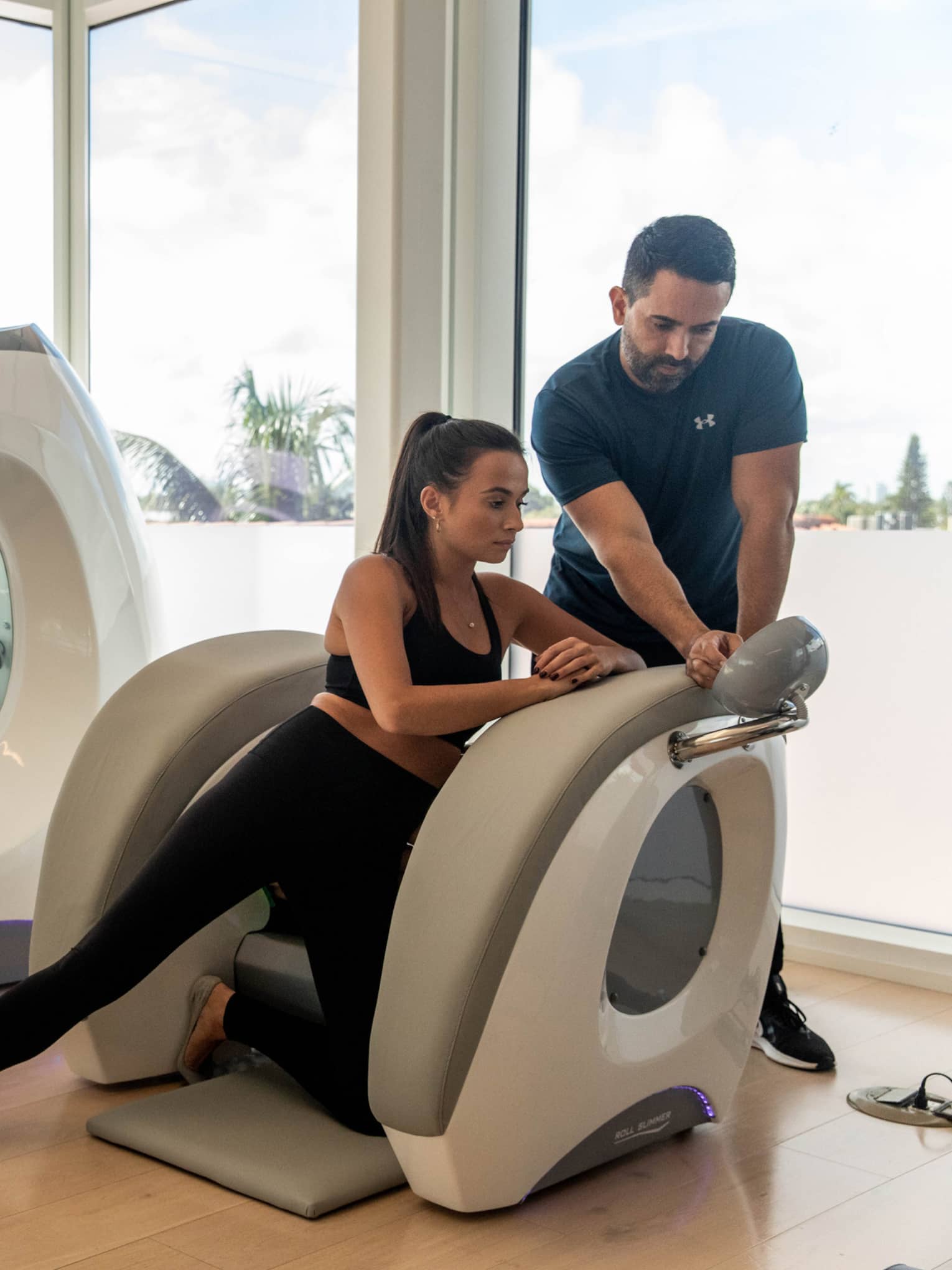 A woman in a machine with a wellness practitioner assisting her.