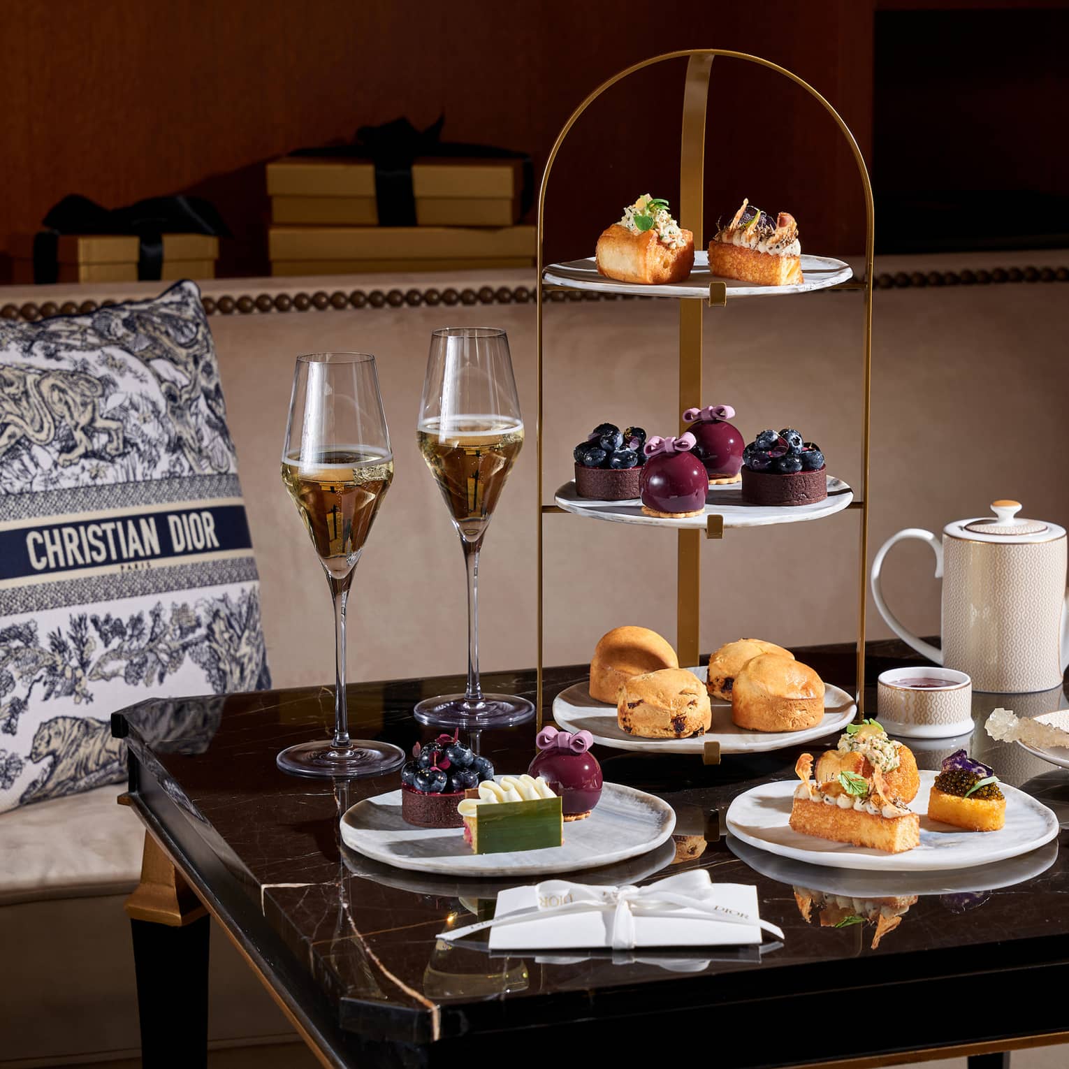 Christmas afternoon tea setup on square table beside banquette set with a black-and-white Christian Dior pillow