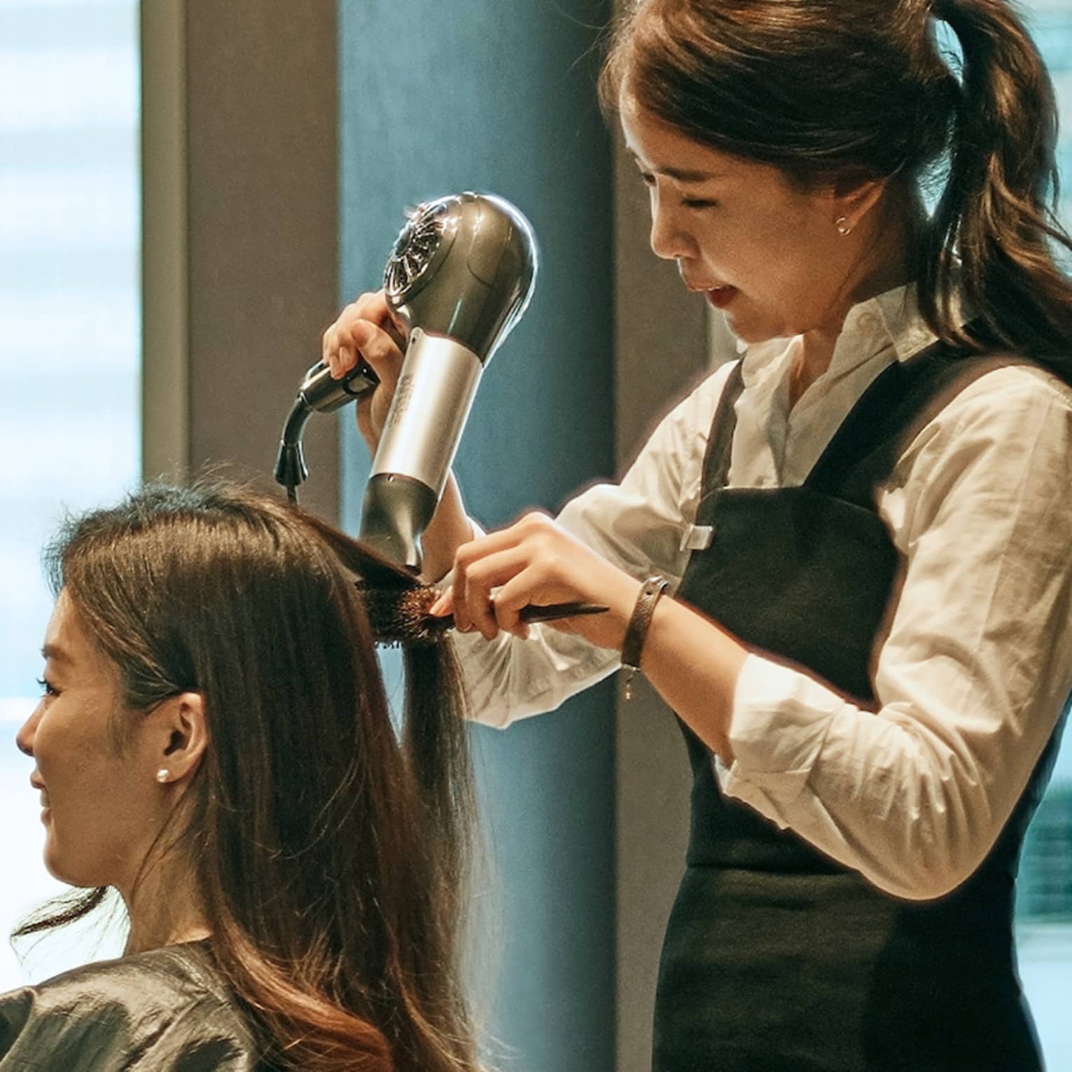 Hair stylist blow dries woman's hair in hotel salon