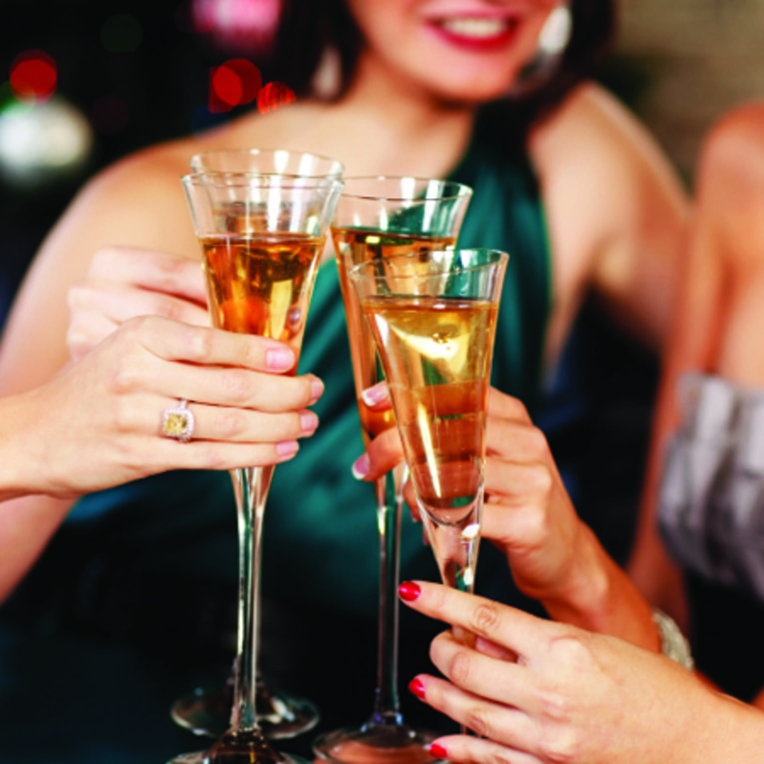 Close-up of women in evening gowns toasting with glasses of Champagne