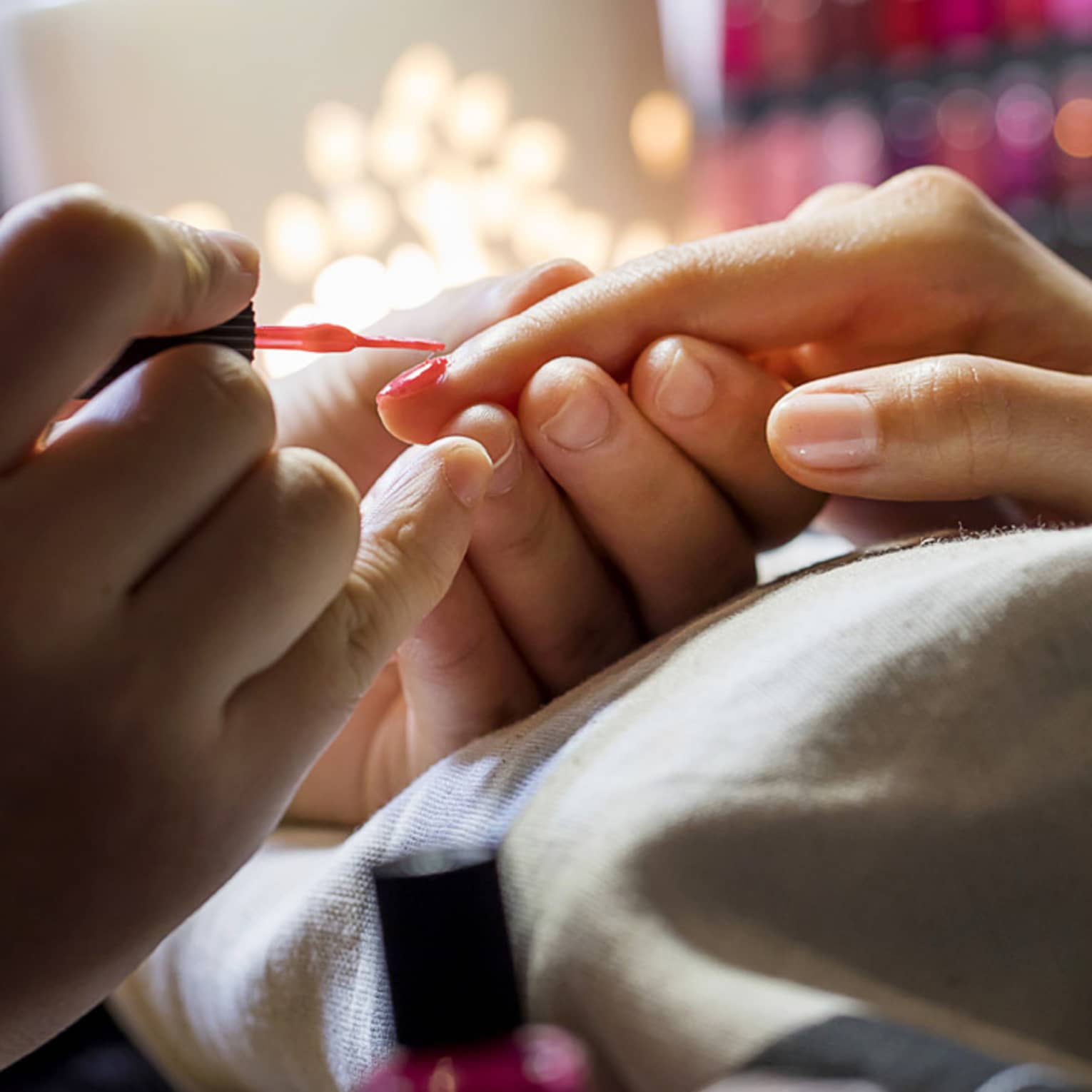 Close-up of manicure, hands resting on pillow as nails painted