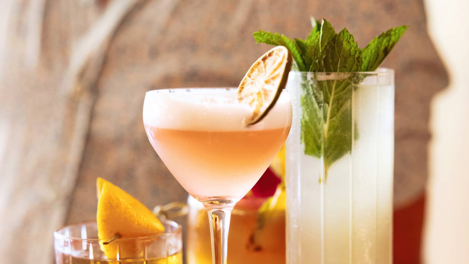 Four different cocktails on a wooden serving board