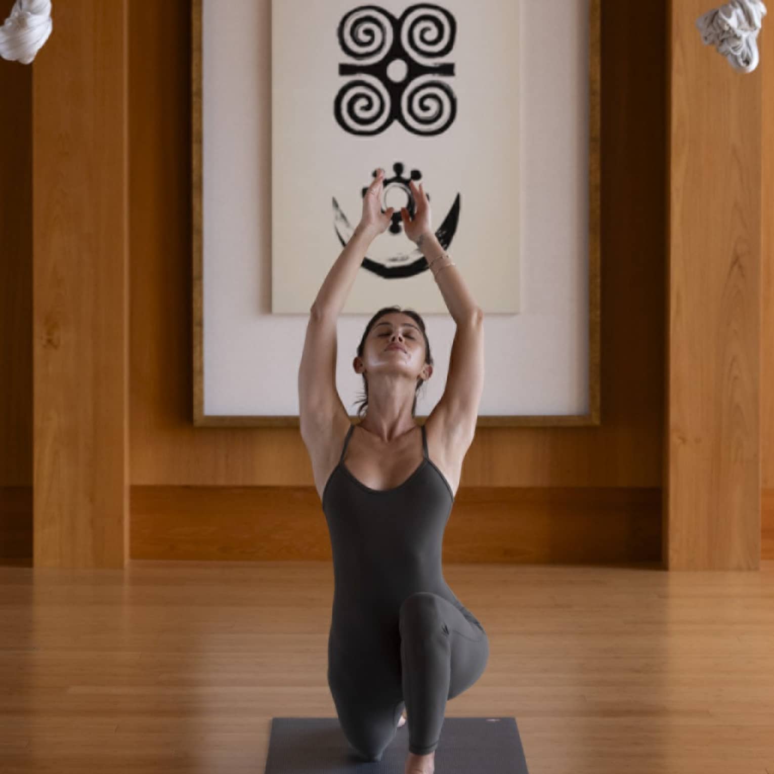 Woman practises yoga in indoor studio with wooden floors and walls