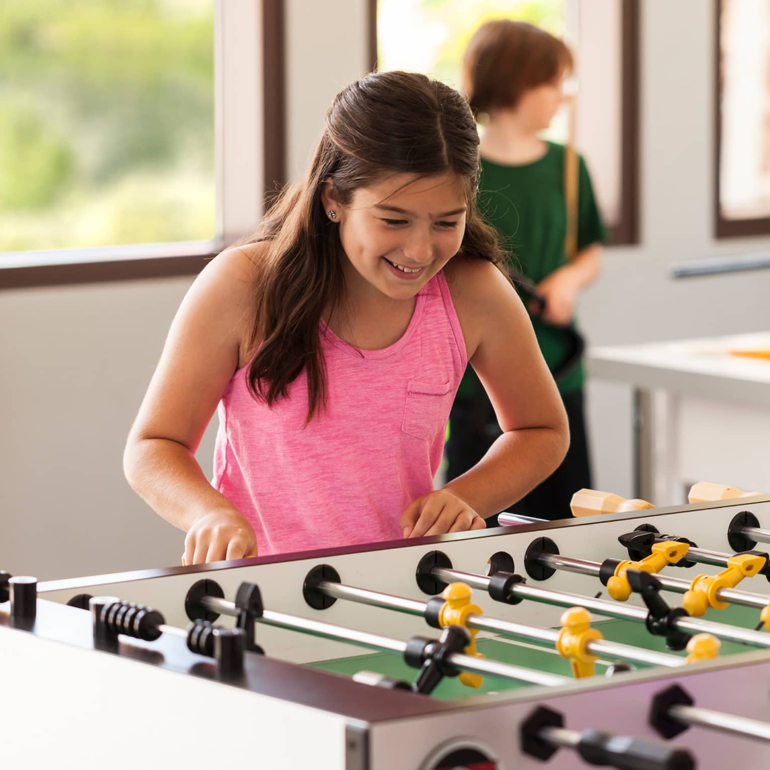 Young teens play table soccer in sunny Teen Centre activity room