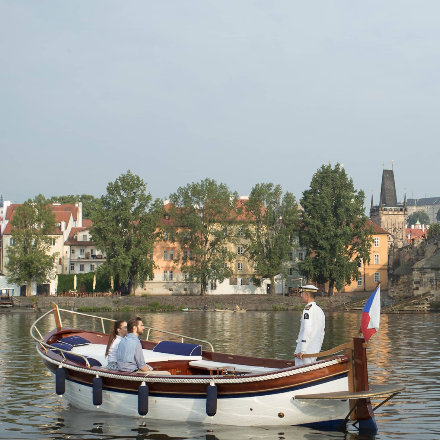 Couple enjoy river boat trip in Prague near small bridge
