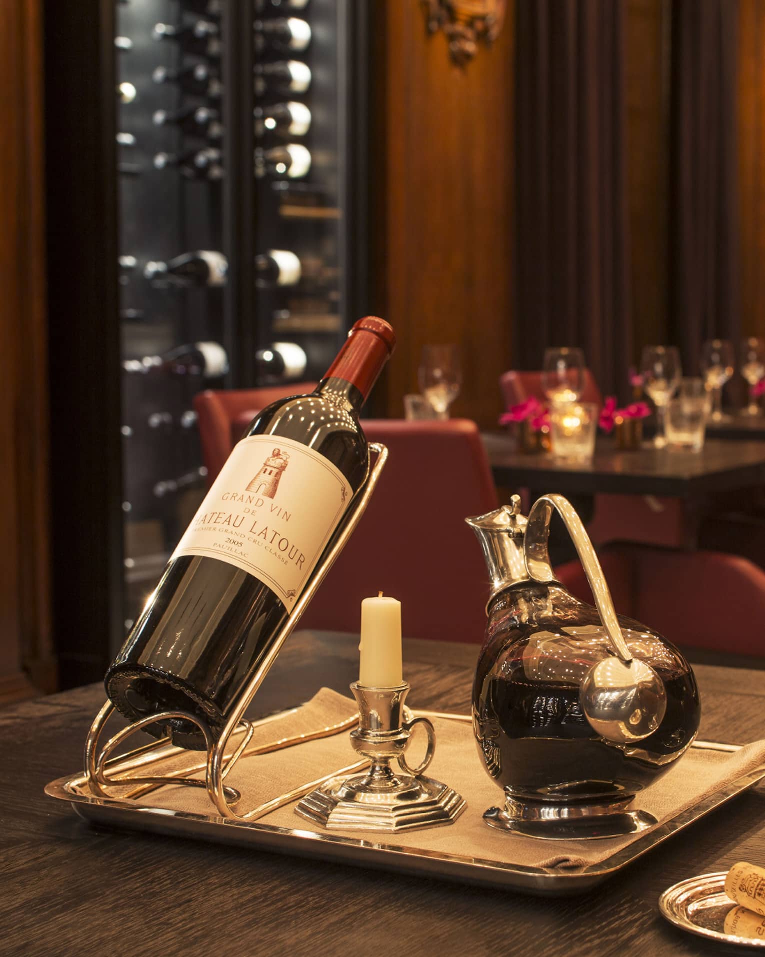A bottle of red wine, a decanter and two glasses in a dimly lit restaurant.